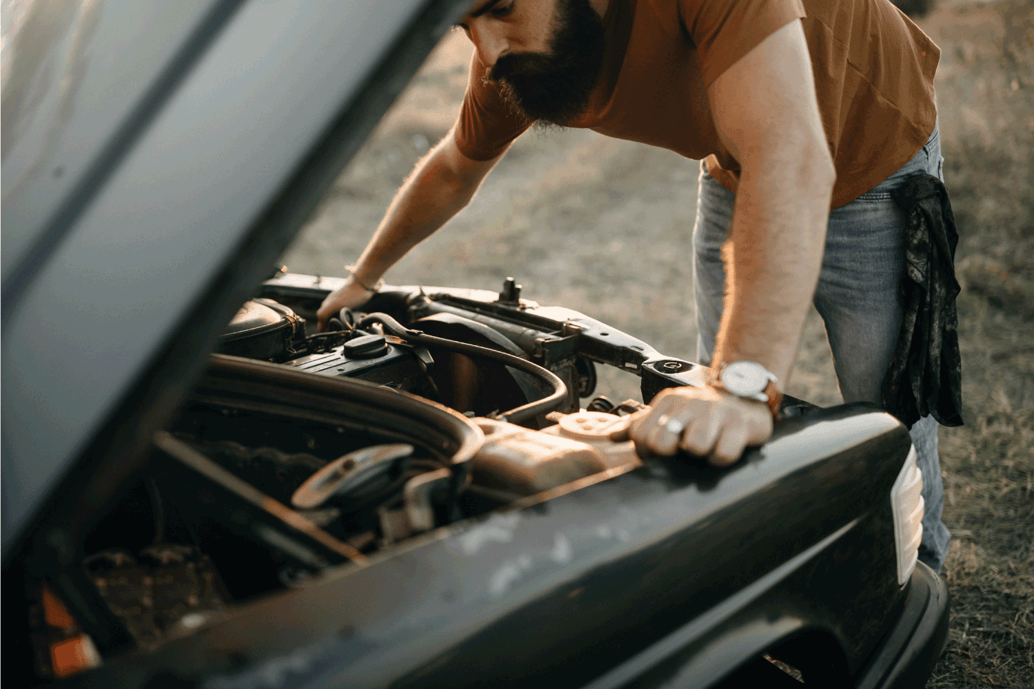 young man is fixing his car