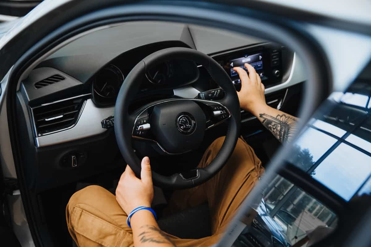 A man's hand holds the steering wheel of a car.