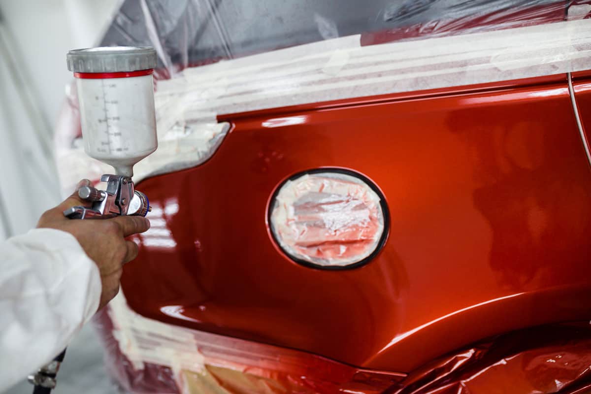 Car auto detailer spraying red paint