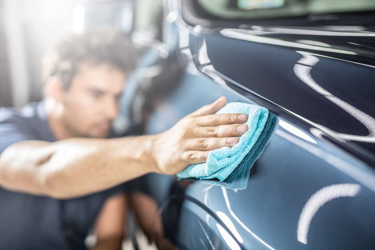 Car detailing - the man holds the microfiber in hand and polishes the car. 