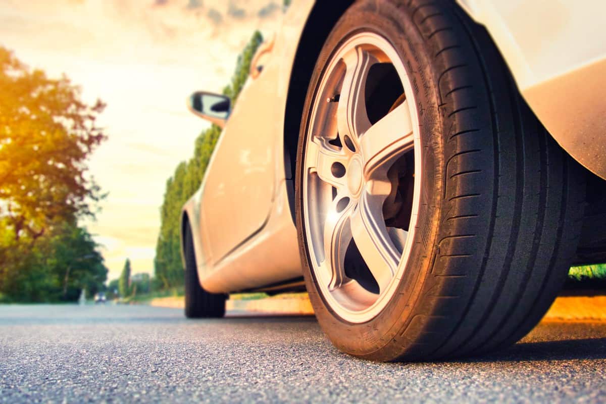Car tire close up on asphalt road at sunset