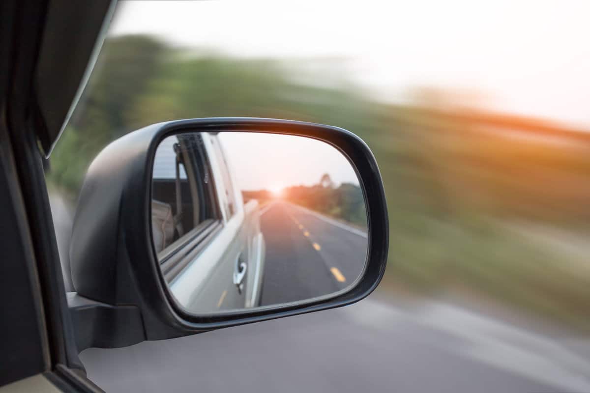 Cars run through the street from the Gray car's side view mirror. Road Car Rear View Mirror Motion Blur Background (Vintage Style)