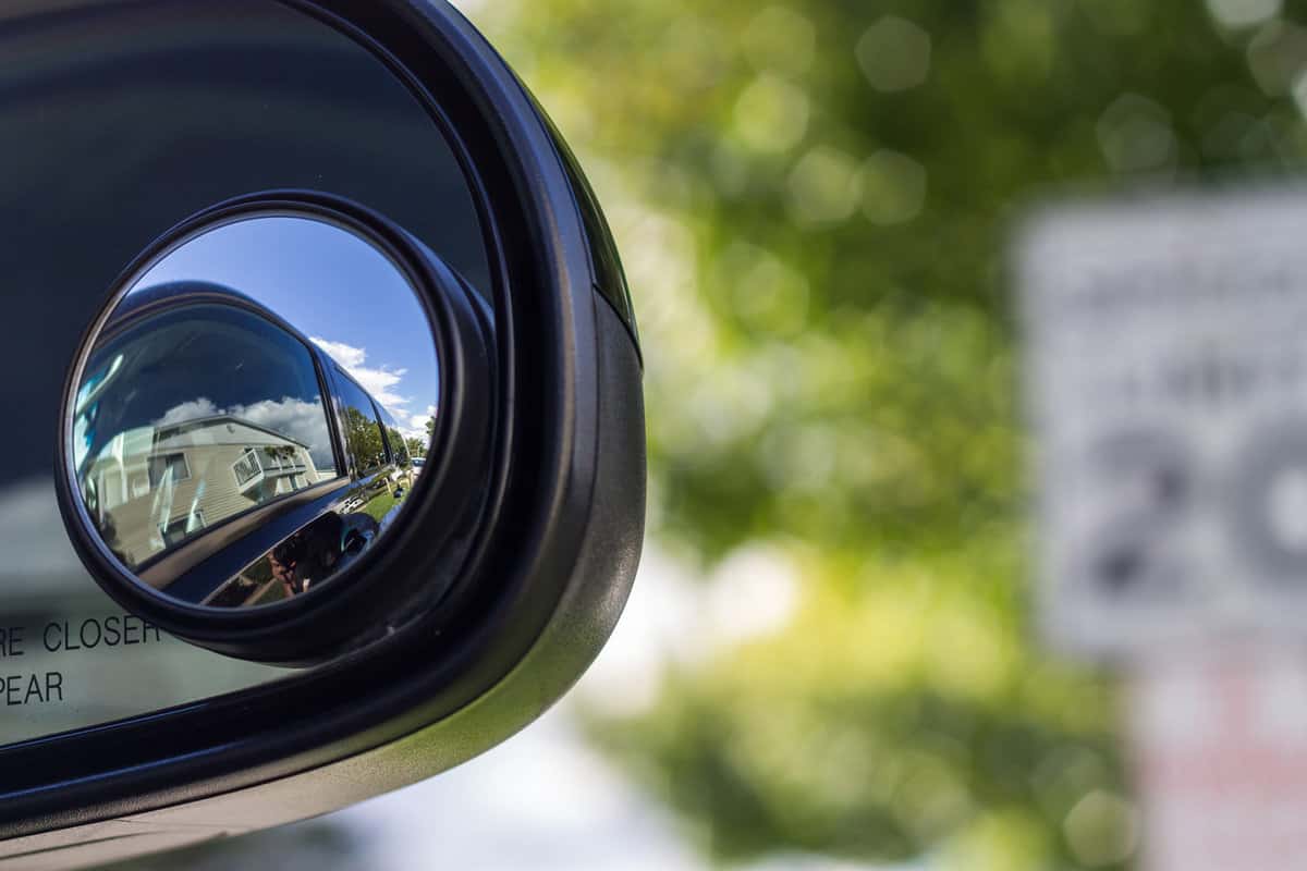 Close up of a blind spot mirror on the passenger side with a blurred background