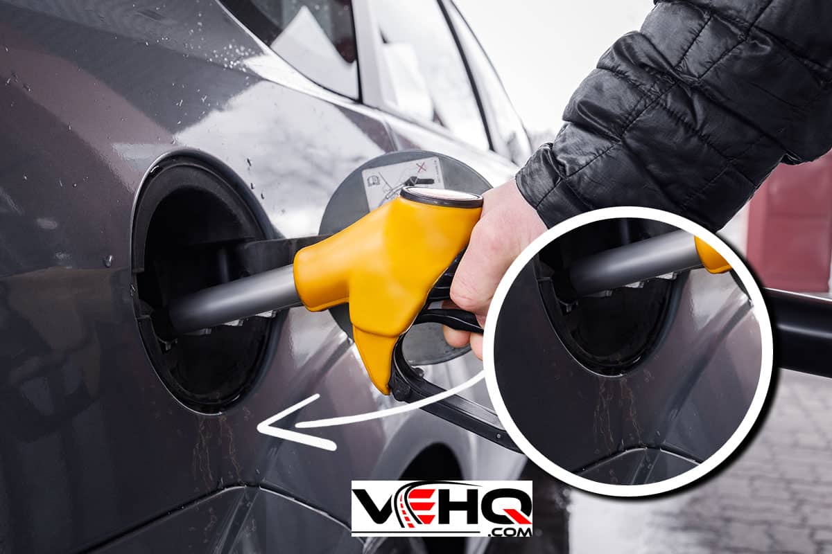 a yellow refueling gun inserted into the opening of the car gas tank, How To Remove Painted Pinstripe From Car, Does Gasoline Damage Car Paint?