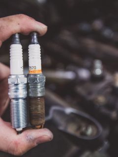 Holding old and new car spark plugs on engine, Spark Plugs Keep Going Bad - What's Wrong?
