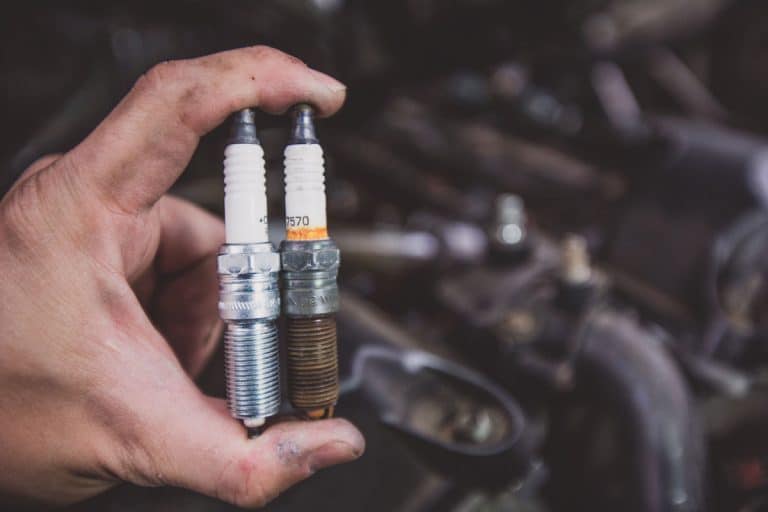 Holding old and new car spark plugs on engine, Spark Plugs Keep Going Bad - What's Wrong?
