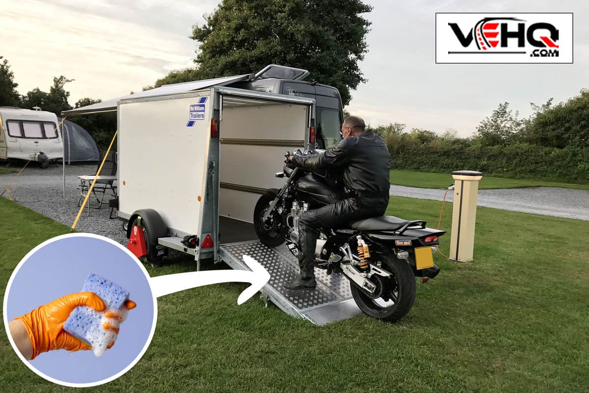 Yamaha XJR 1300 motorbike with motorcycle rider riding the bike into a secure covered trailer with red metal wheel lock on a campsite, How To Clean Toy Hauler Ramp Door
