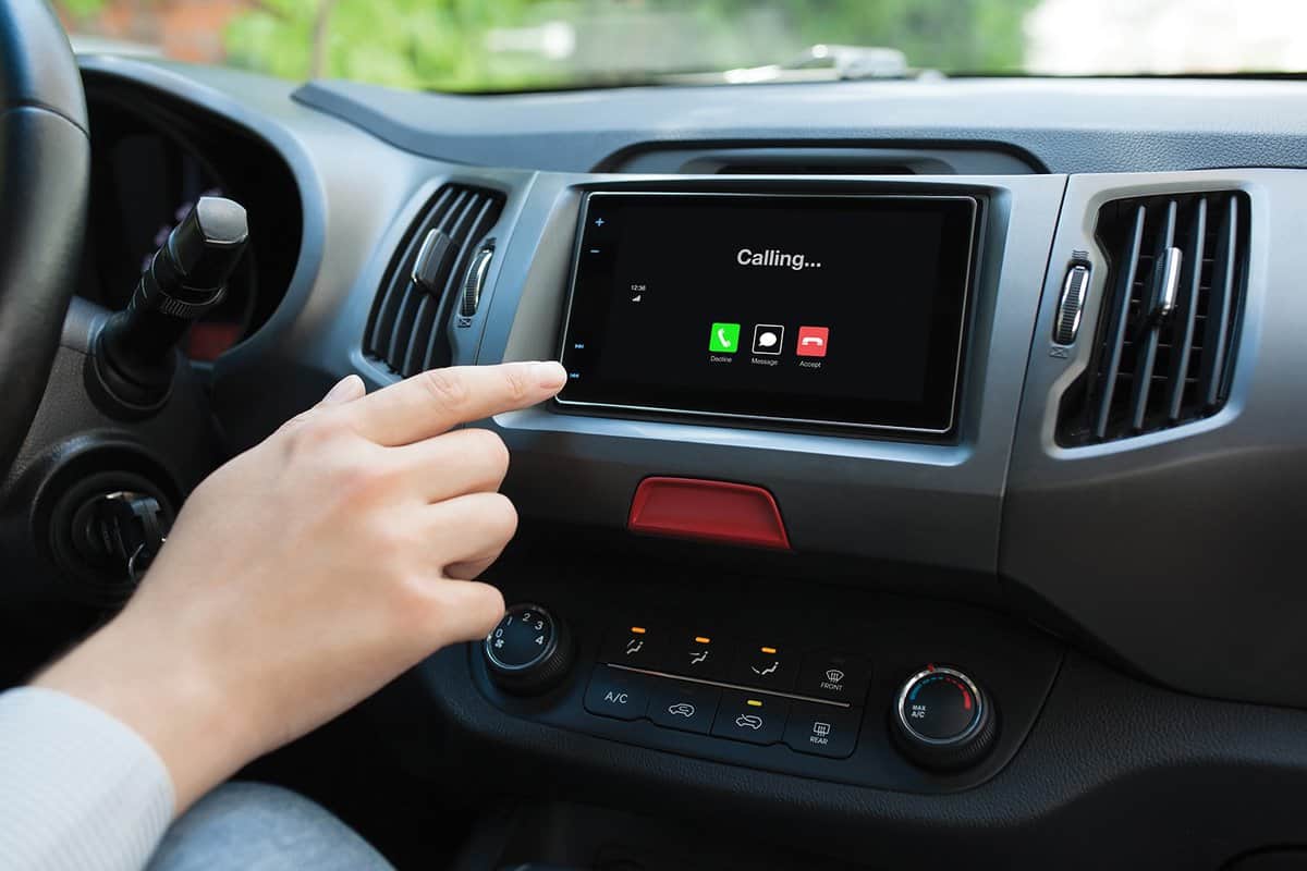 Man hand touching multimedia system with phone calling on screen in car