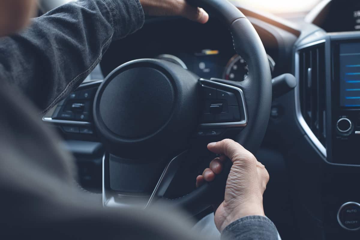 Man hands holding steering wheel, driving a car through slight turn, close up