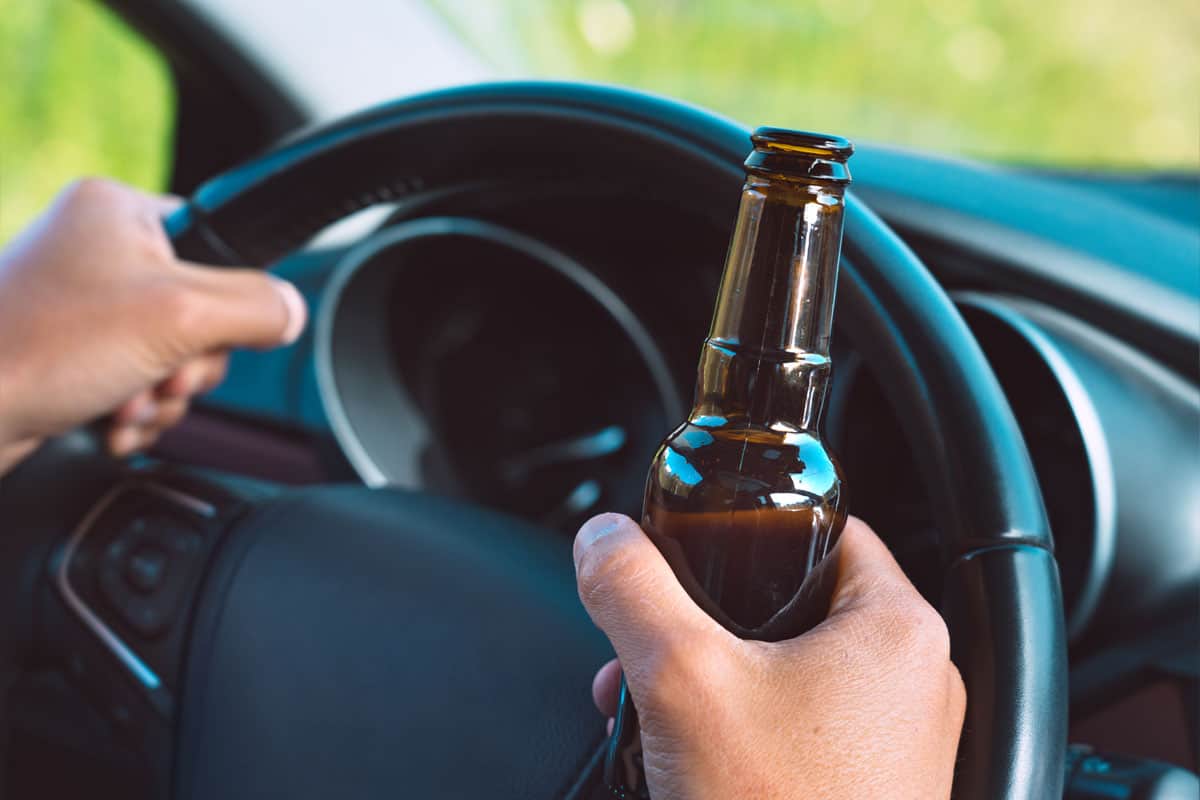 Man holding a beer whilst driving his car