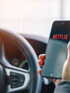 Man opening Netflix app on Apple iPhone in a car