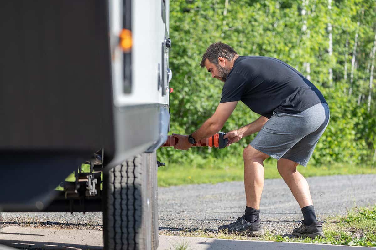 Man rmptying RV sewer at dump station after camping
