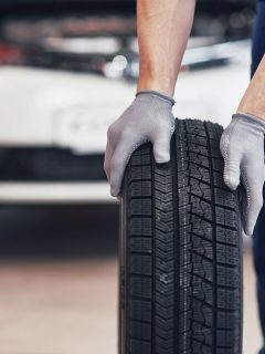 Mechanic holding a tire tire at the repair garage, Are 275 Tires The Same As 33?