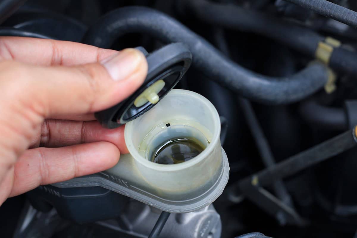 Mechanic opening brake fluid cap for car maintenance