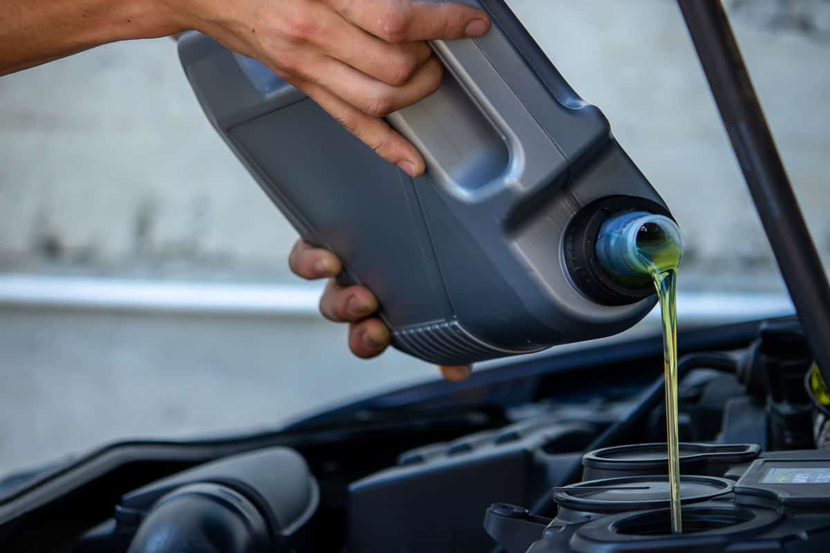 Mechanic pouring new oil to the car engine