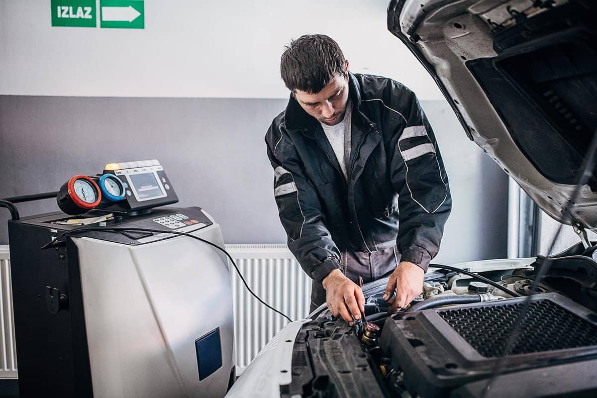 Mechanic recharging car air-condition in auto repair