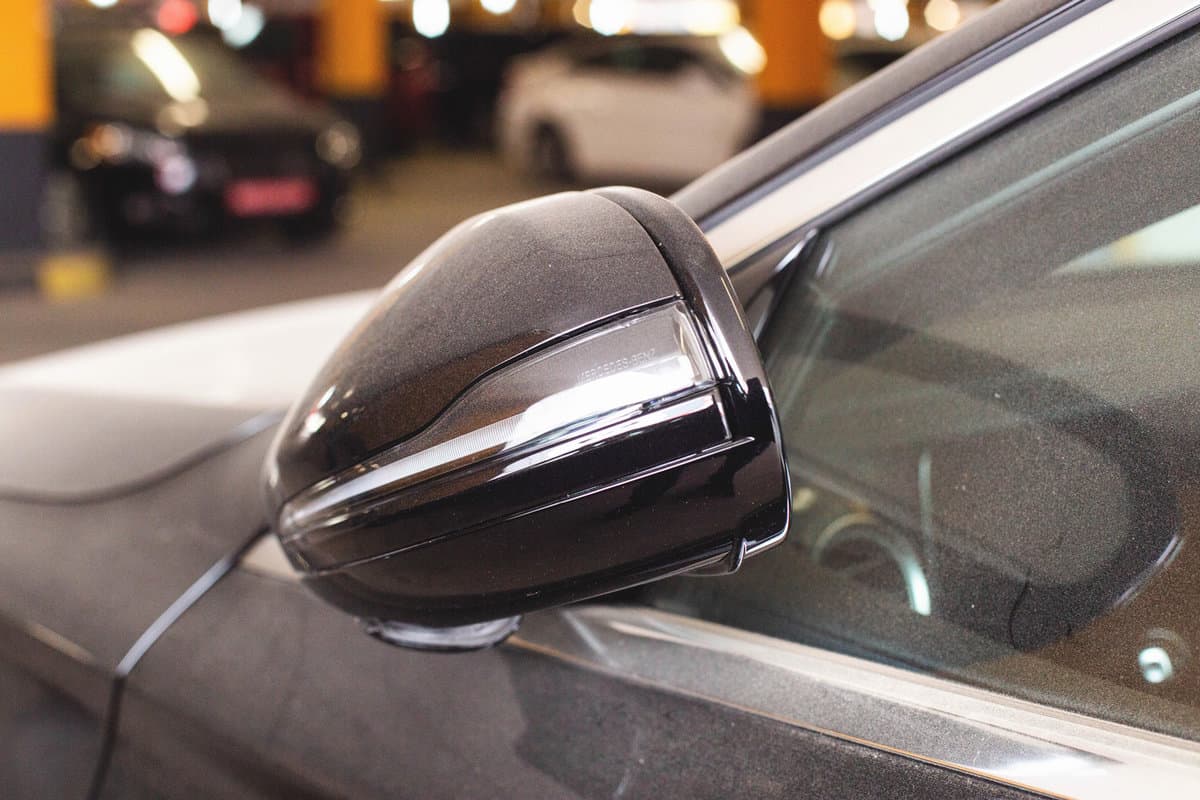 Modern folding car mirror with turn signal. Black car, close-up. Exterior