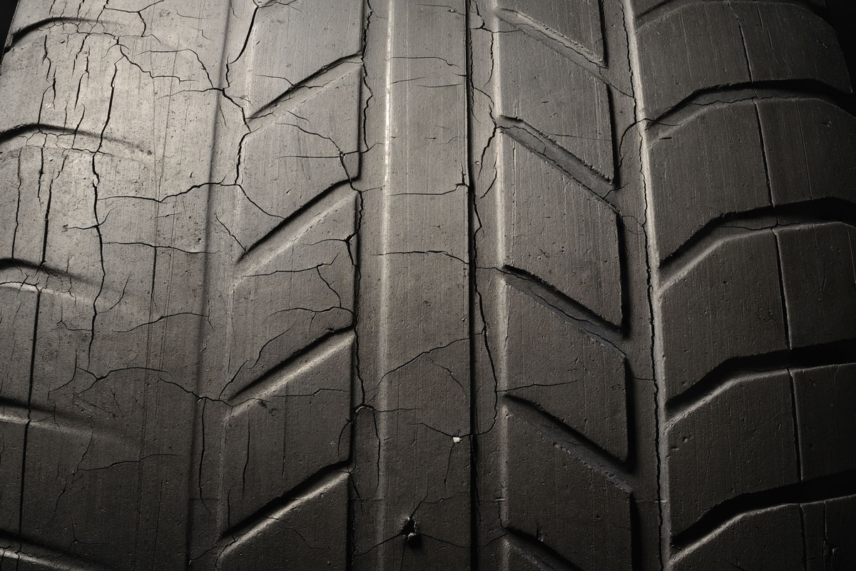 Old damaged, worn black tire tread, large cracks in the car wheel, tire black