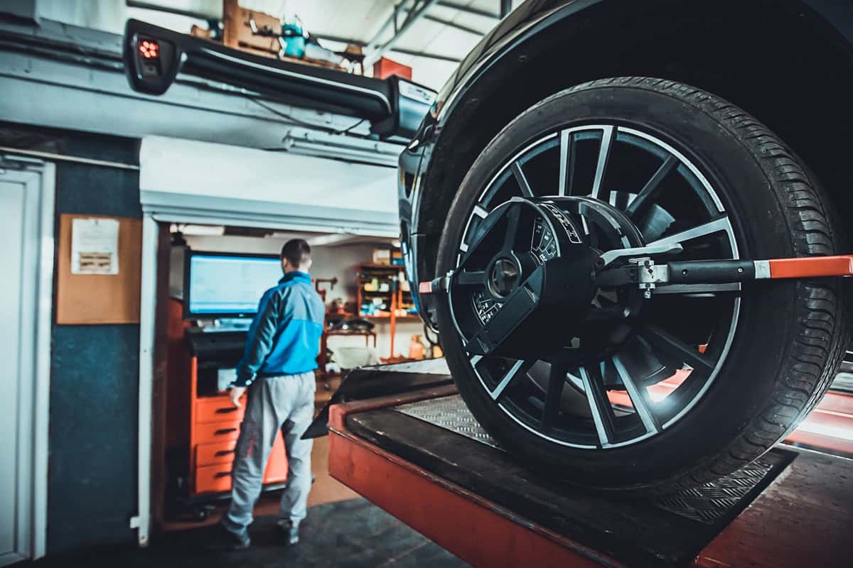 One man, mechanic in auto repair shop, wheel alignment equipment on a car wheel in a repair station.