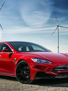 Photograph of a red Tesla model S in front of a windmill field - How Much Does It Cost To Fix A Dent In A Tesla