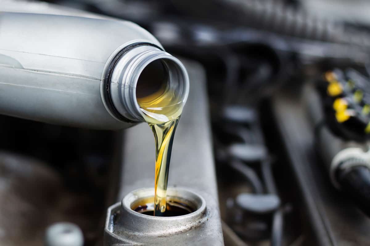 Poured engine oil to the car engine. The mechanic exchanges the oil in the car
