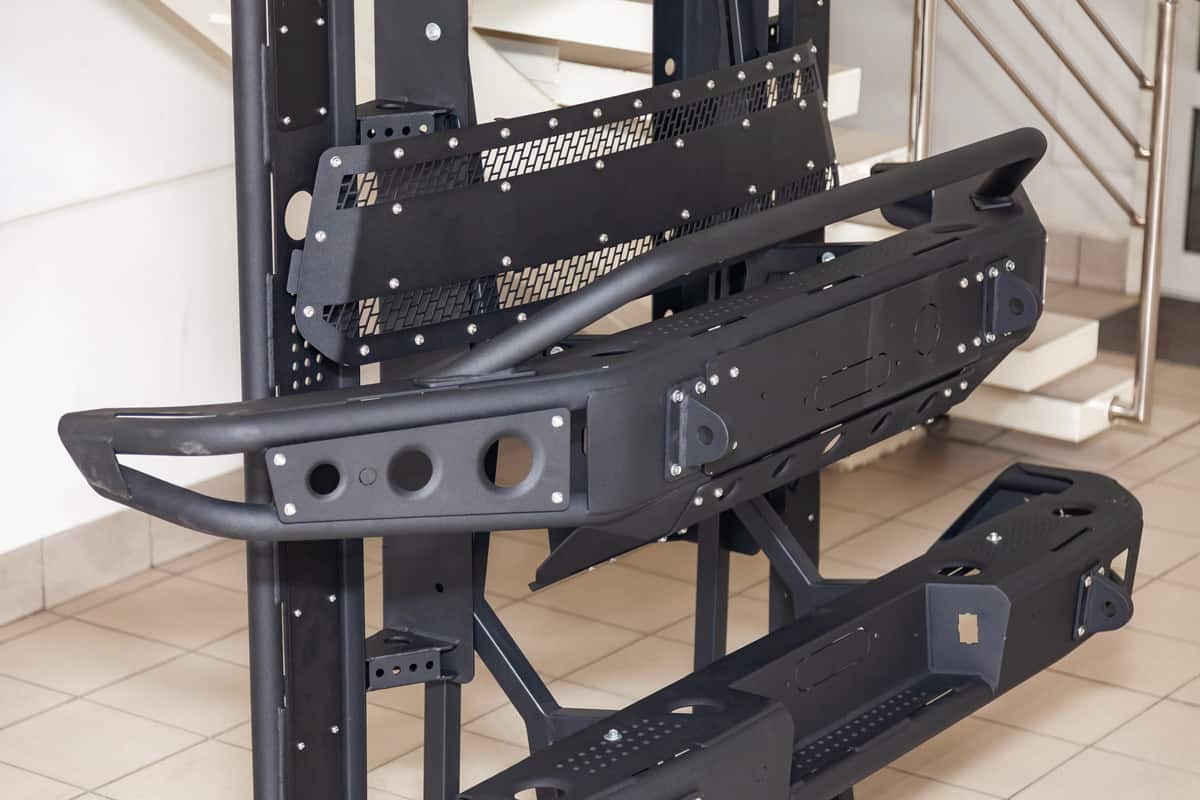Stand for demonstration of car body elements reinforced for off-road and made of metal, such as bumper, steps and black grille in the workshop for the installation and tuning of SUV vehicles.