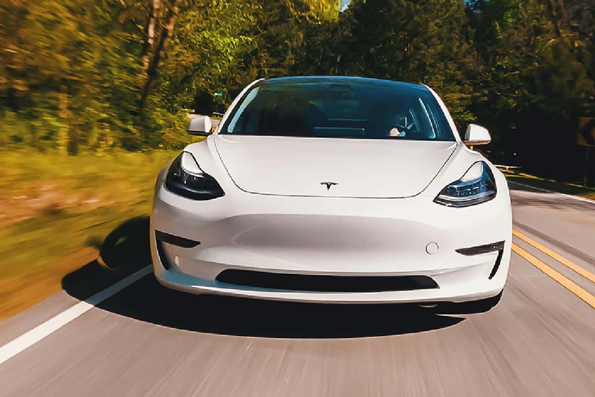 Tesla Model 3 all electric vehicle driving down a country road