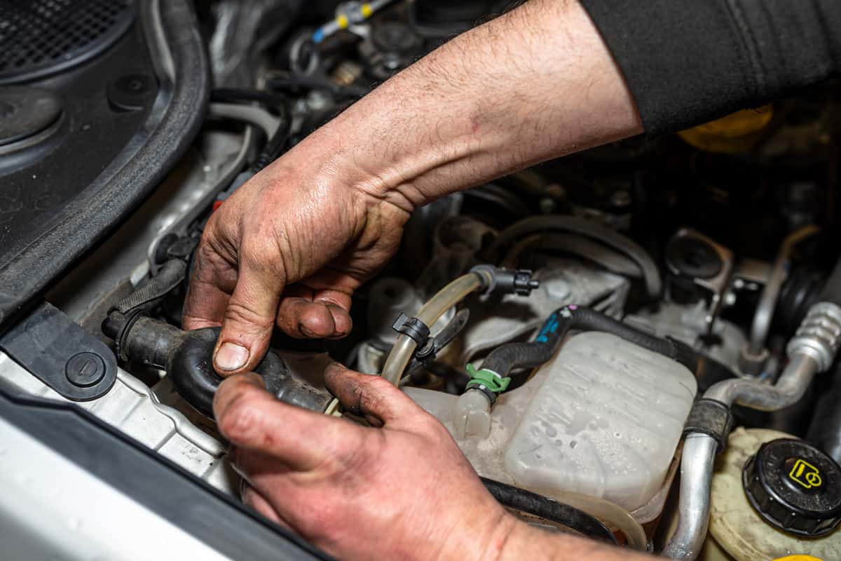The mechanic bleeds the fuel system with a pump that is on the fuel line, after installing a new fuel filter, the man hands are visible.