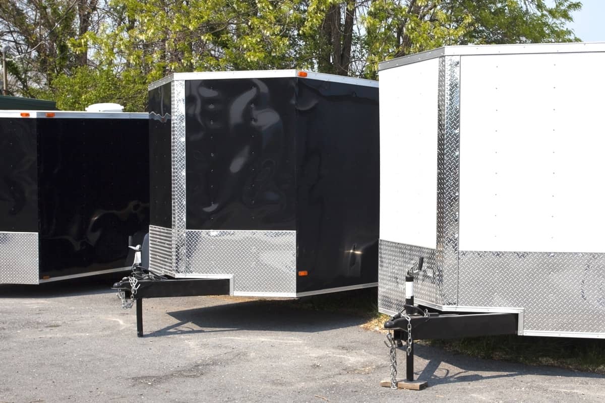Three black and white transport trailers for sale or rent in a row.