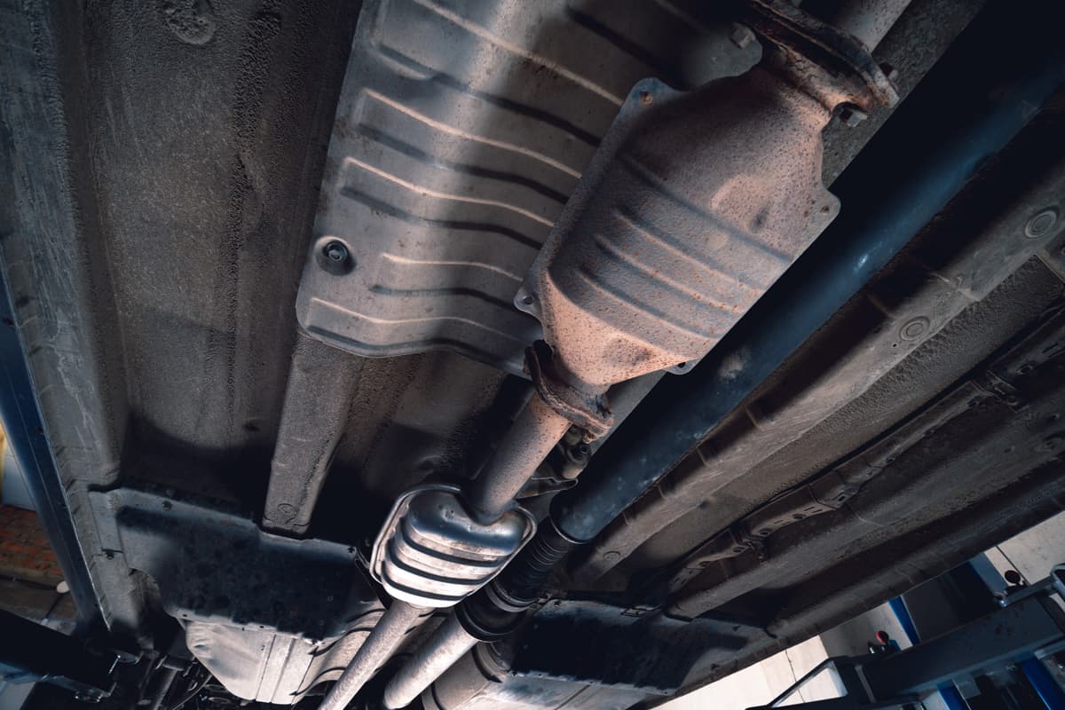 Vehicle underbody exhaust pipe, catalyst, resonator, exhaust system. Old parts require repair and replacement. Car service and maintenance. cardan and outboard bearing.