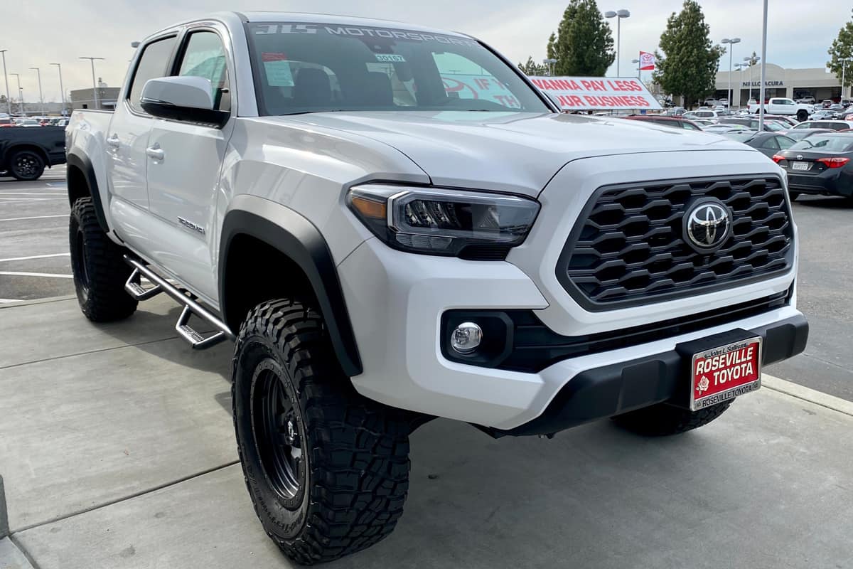 White Toyota Tacoma pick up truck 2020 year model on a dealership lot.