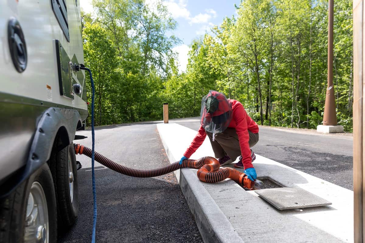 Woman holding a hose remove sewer water from the RV