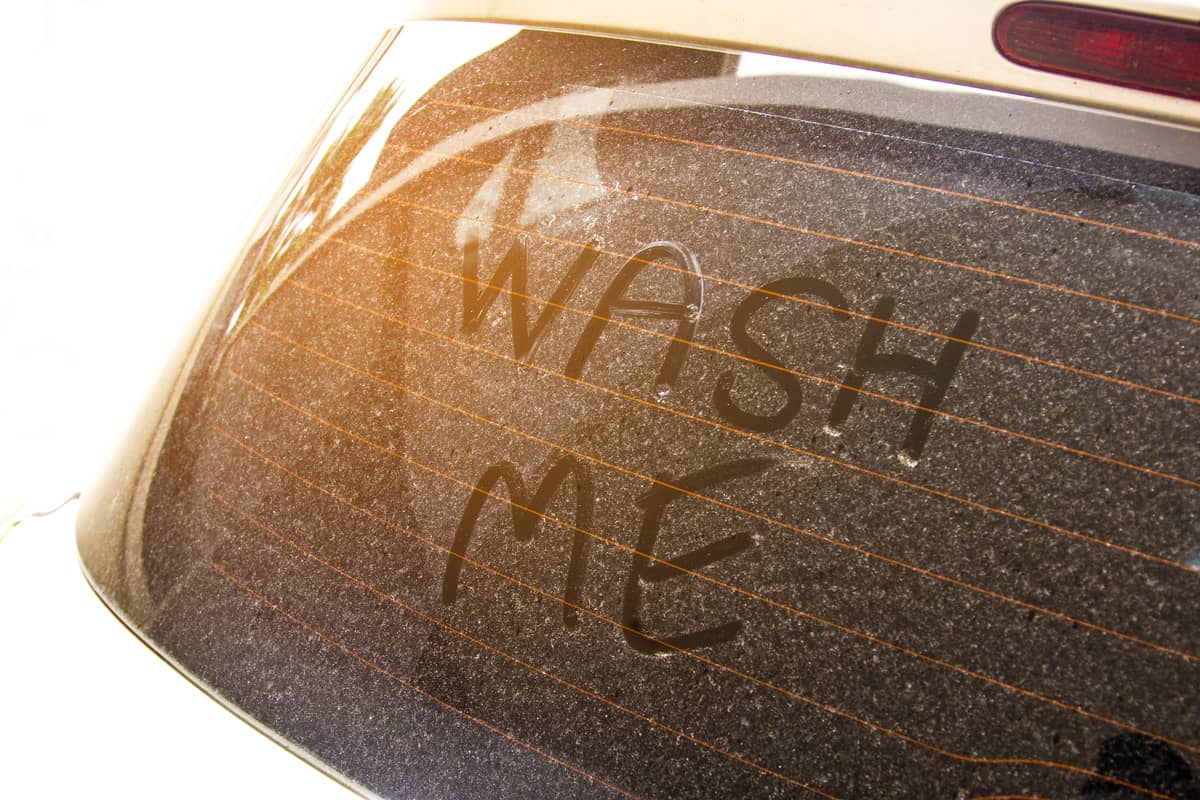 Write the words "wash me" on the very dirty surface of the car. Concept car wash.