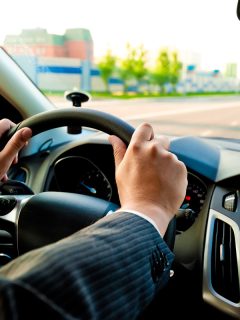 man holds the steering wheel firmly with both hands, Steering Wheel Not Returning To Center - What Could Be Wrong?