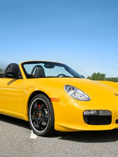 A yellow Porsche Boxster limited edition convertible with black wheels and red brake calipers parked on a blue sky day, What Is The Best Oil For Porsche Boxster?