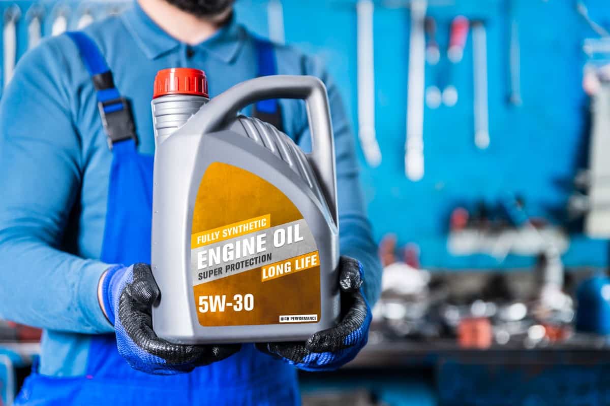 Auto Mechanic Showing 5W-30 Engine Oil in the Auto Repair Shop