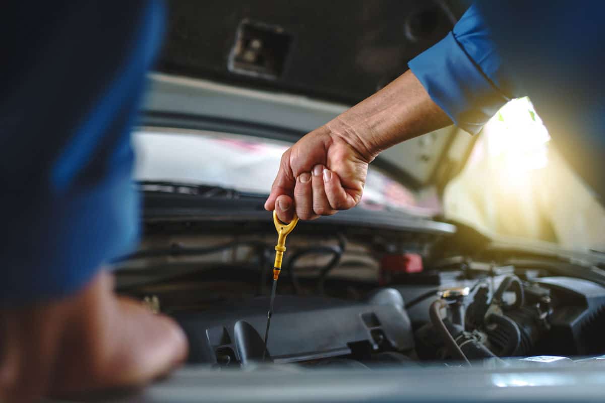 Auto mechanic is checking the engine oil in a vehicle at the garage