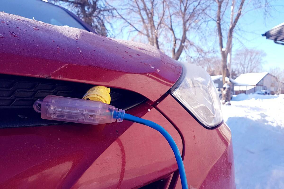Block heater cable, plugged into a vehicle parked in a snowy winter driveway.