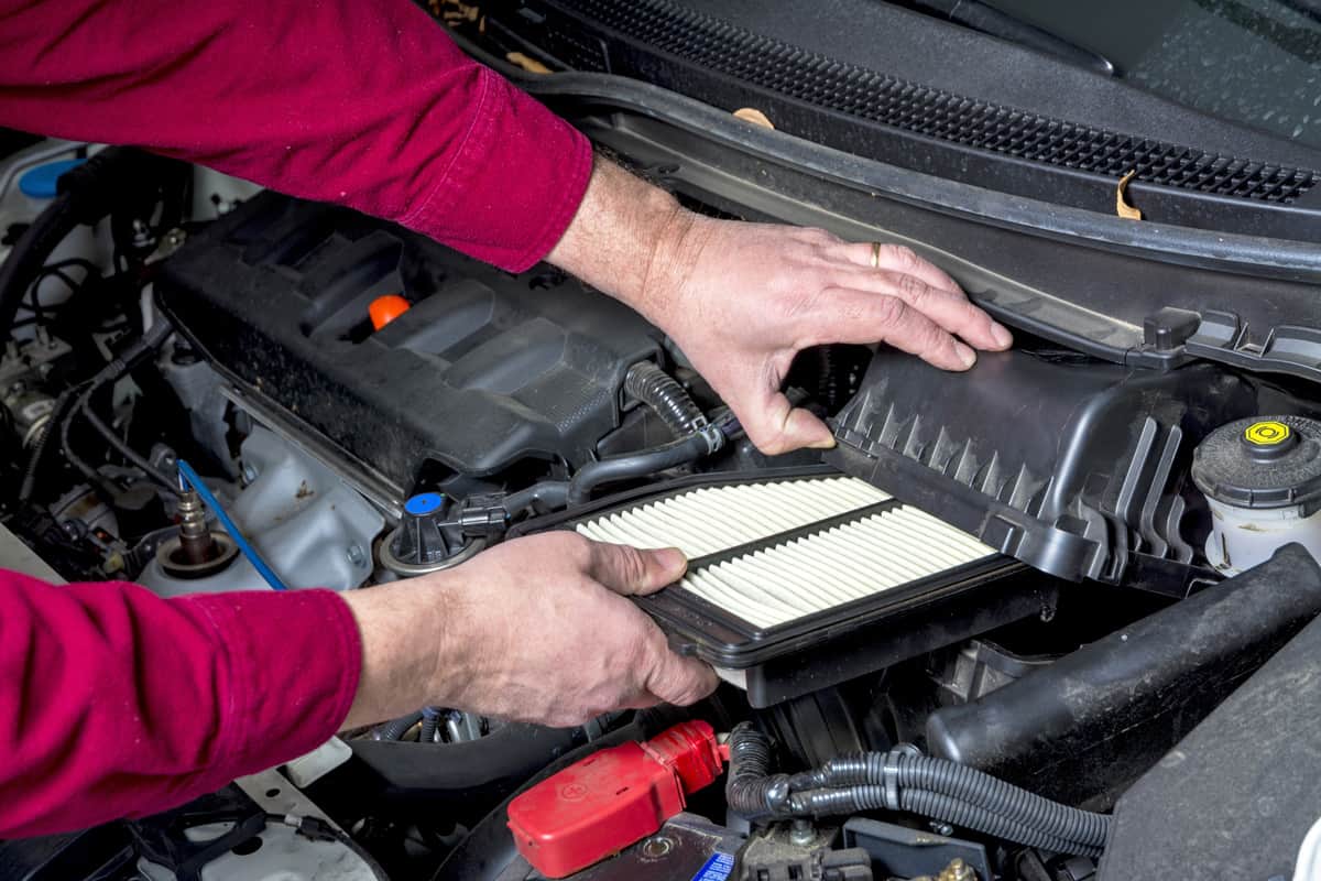 Car mechanic slipping in a new car air conditioning filter