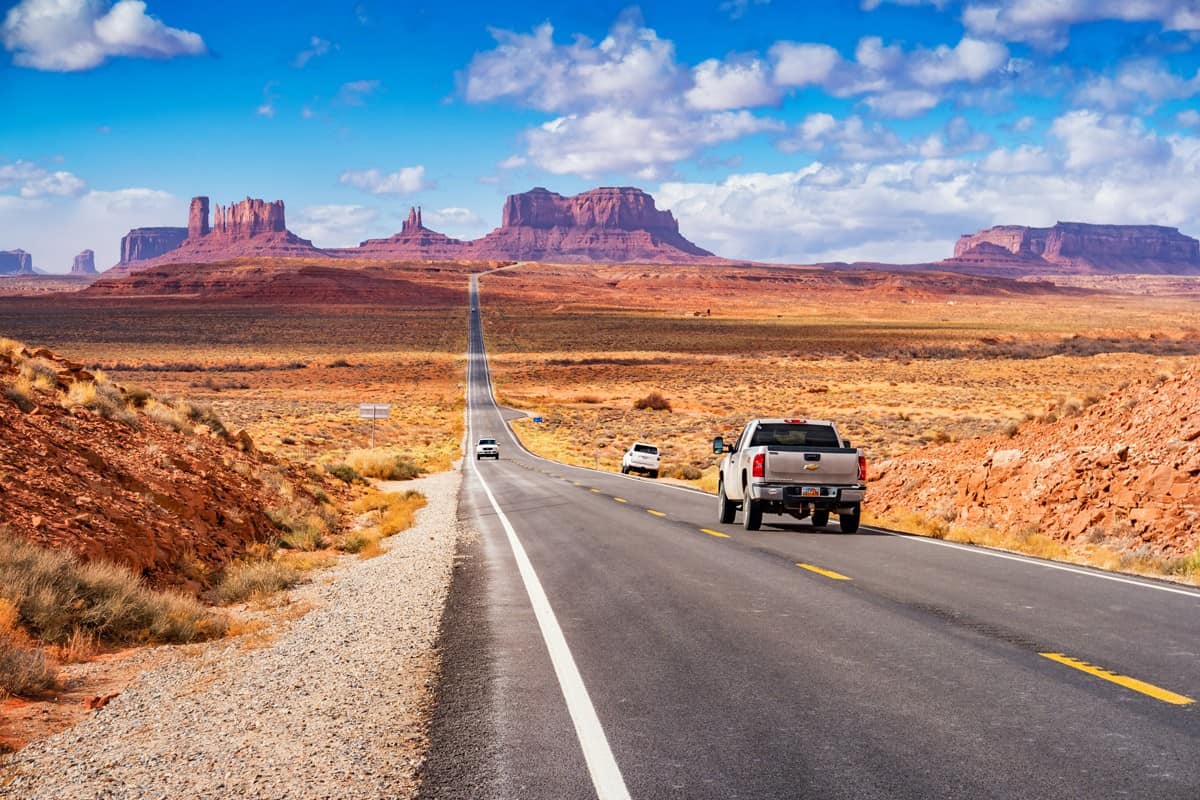 Cars drive at Forrest Gump Point in Monument Valley Utah USA 