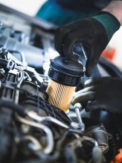 Close up hands of unrecognizable mechanic doing car service and maintenance. Oil and fuel filter changing - Can A Clogged Oil Filter Make Your Engine Knock