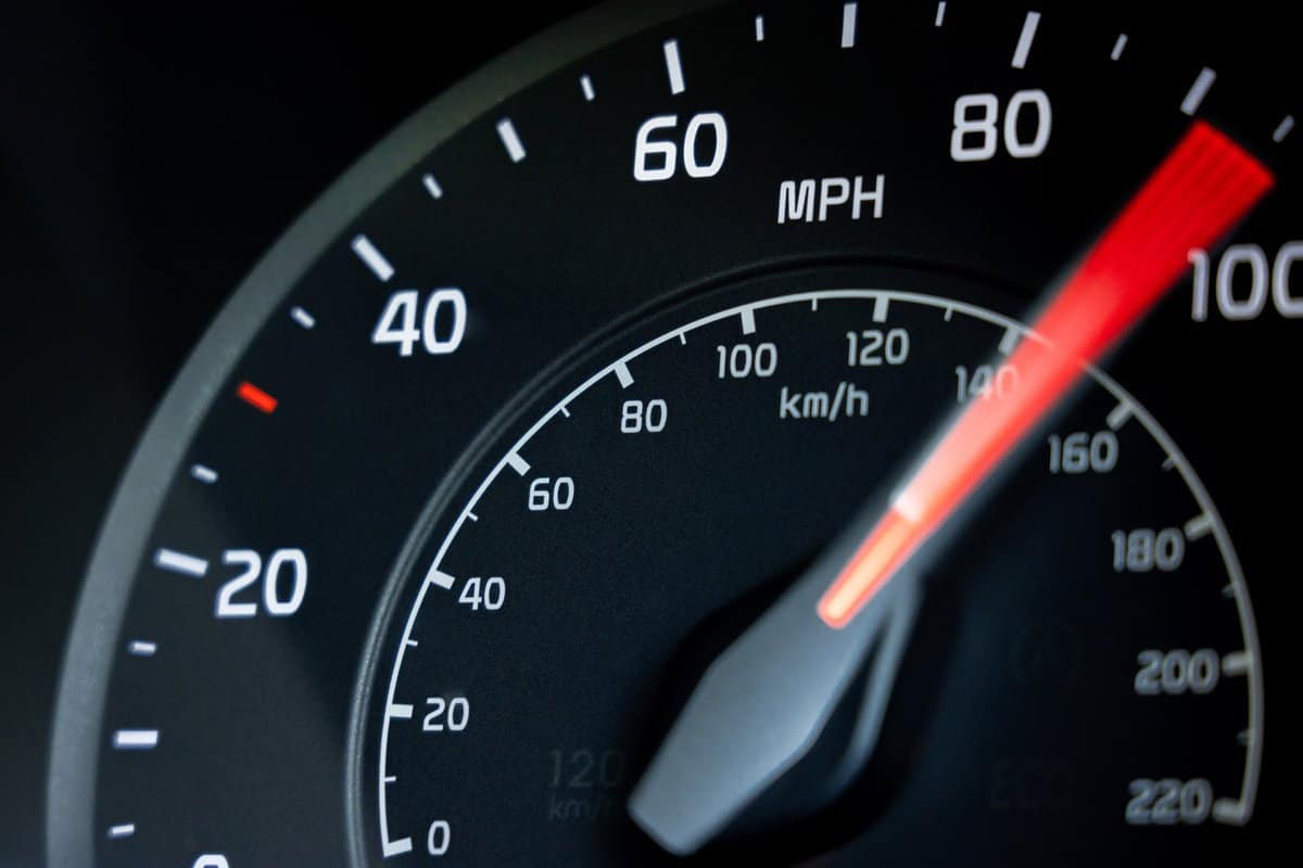 Close-up showing the needle on a car's speedometer moving towards 100 miles per hour.
