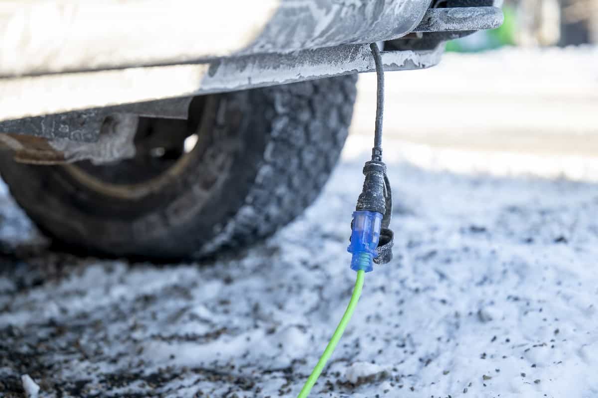 Closeup of extension cord plugged into vehicle on cold day