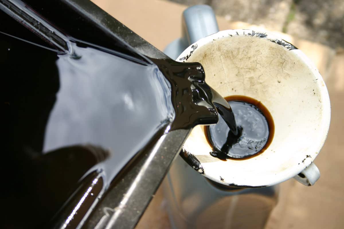 Dirty oil being poured into a canister throug a funnel