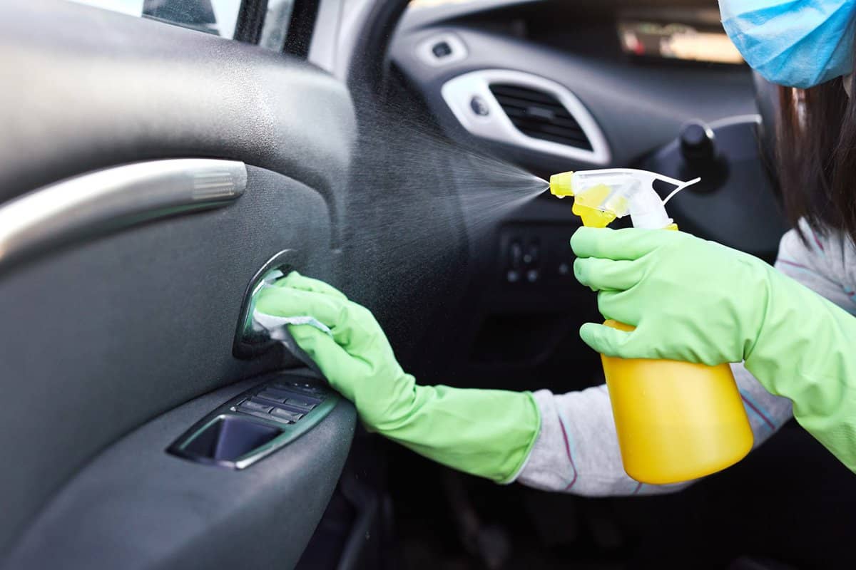 Female hand spraying sanitizer and antiseptic wet wipes for disinfecting car