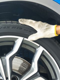 Hand of mechanic on the tire to check the Tire Size numbers and Tyre Load Indexes on the sidewall.