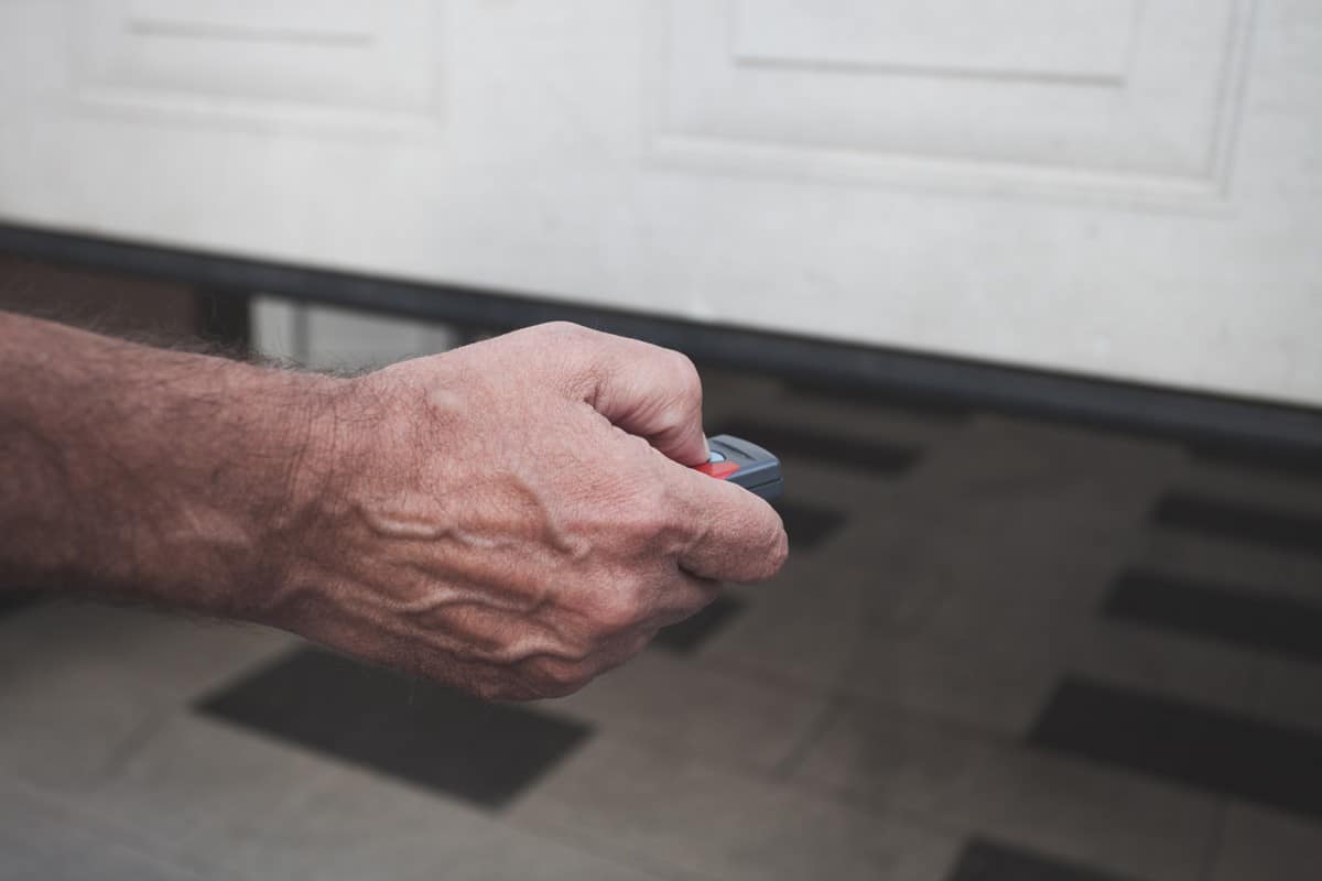 Man hand open the garage door with remote control closeup.