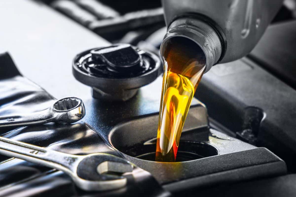 Pouring motor oil for motor vehicles from a gray bottle into the engine, , oil change, auto repair shop, service,
