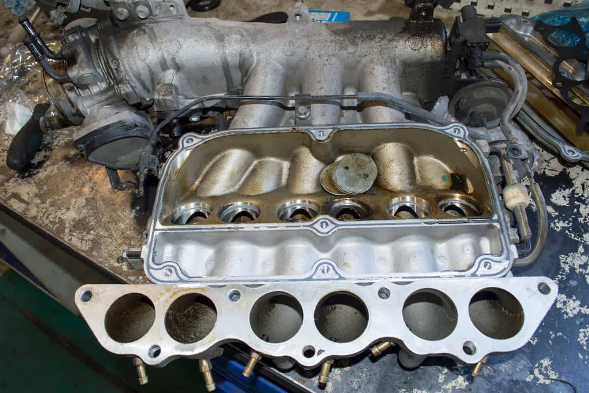 The removed intake manifold of the car engine is on the desktop