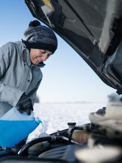 Woman refilling Windshield Washer of her Car with Antifreeze Wiper Fluid Outdoors in Winter - When Should I Put Antifreeze In My Car